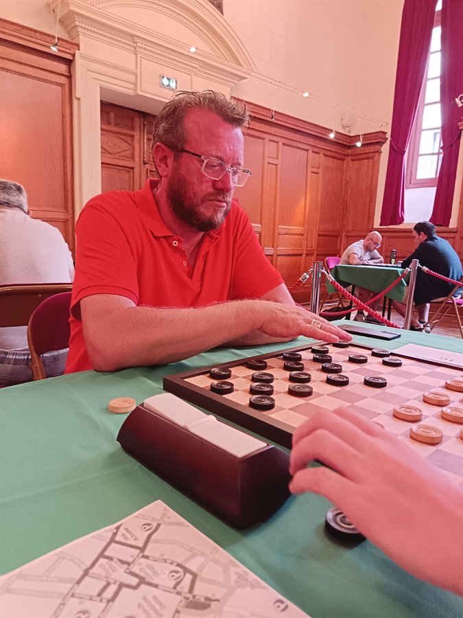 Arnaud Dufour à sa partie de jeu de dames, la main sur les pions