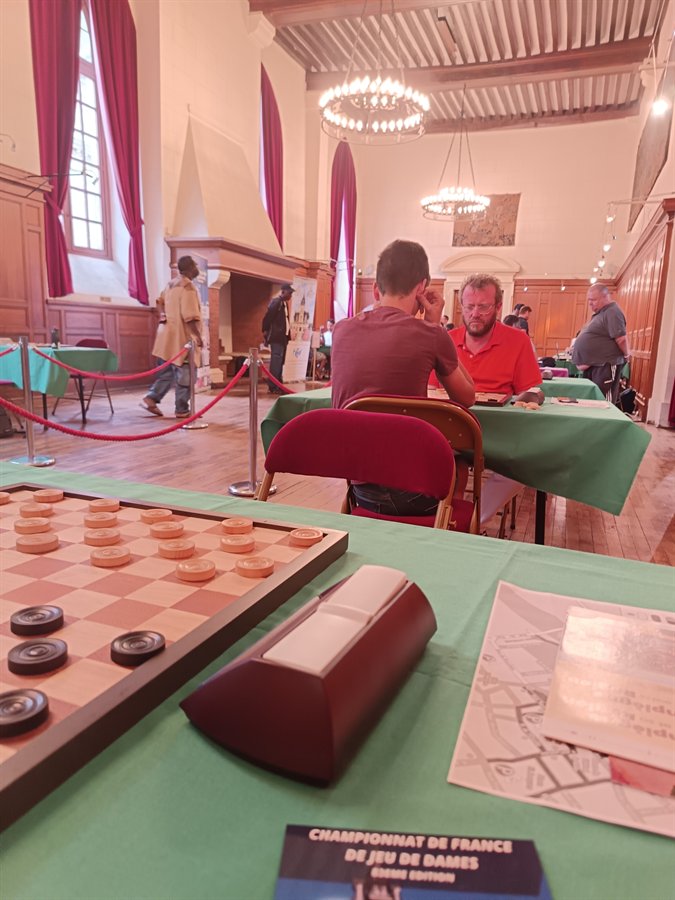 Un damier posé sur une table, la banderole du championnat de France derrière