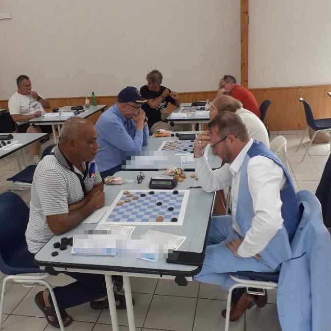 Plusieurs parties de jeu de dames en cours dans la salle d'un tournoi