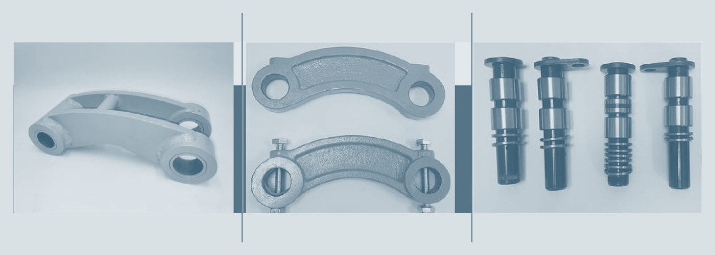 Les trois pièces d'articulation côte à côte : une biellette de godet en acier gris, une paire de biellettes de vérin, et quatre axes montés dans leurs bagues
