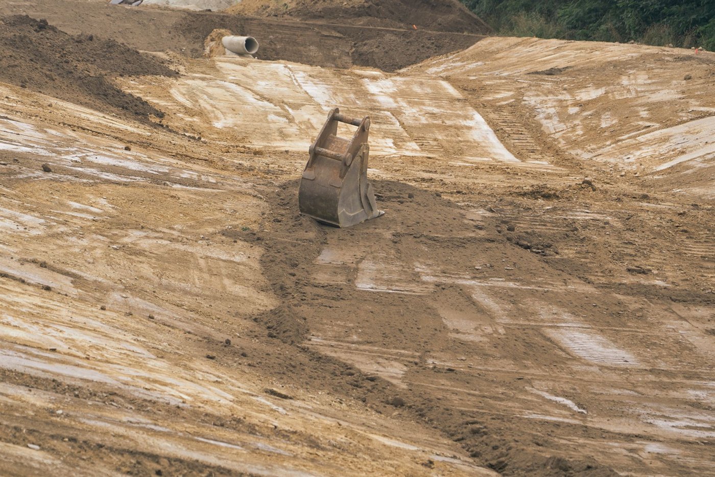 Godet de petite pelle posé debout sur un talus de terre réglé, ses oreilles et ses deux axes tournés vers le haut.