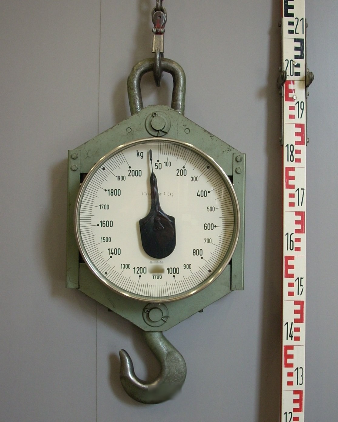Peson mécanique vert à grand cadran gradué jusqu'à 2000 kg, suspendu par une manille, un crochet de levage en dessous.